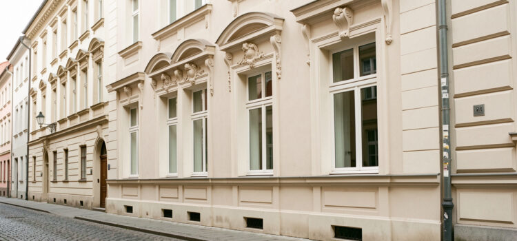 Rénovation façade ancienne : préserver les détails architecturaux Façade ancienne rénovée avec moulures élégantes, encadrements de fenêtres raffinés et enduit clair, éclairée par une lumière naturelle douce.